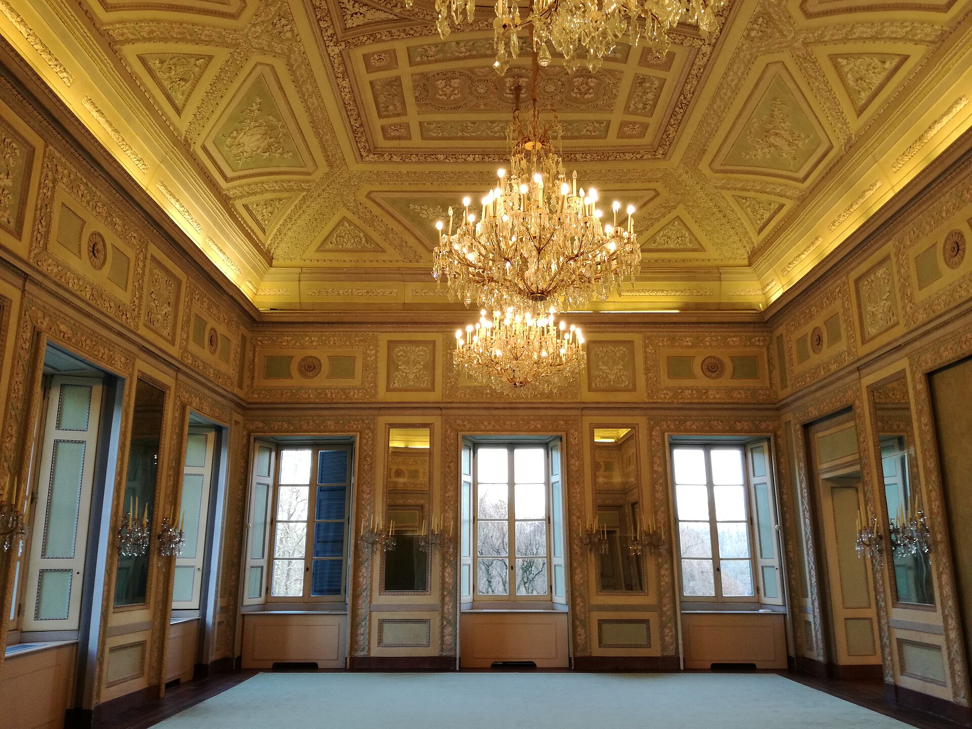 A hall with ceiling and walls richly decorated in stucco, with cornices, panels and gilded reliefs