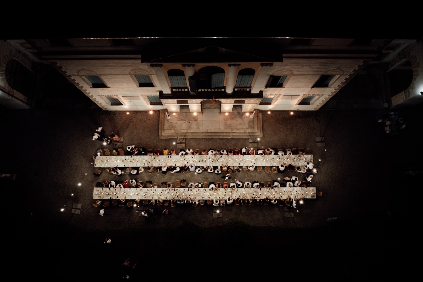 Overhead view of the reception dinner with lit tables in front of the villa's façade
