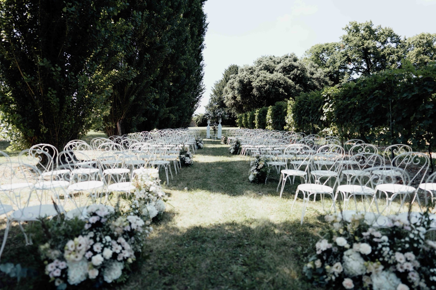 Wedding ceremony set up in the park of a Venetian villa, with white chairs and floral arrangements